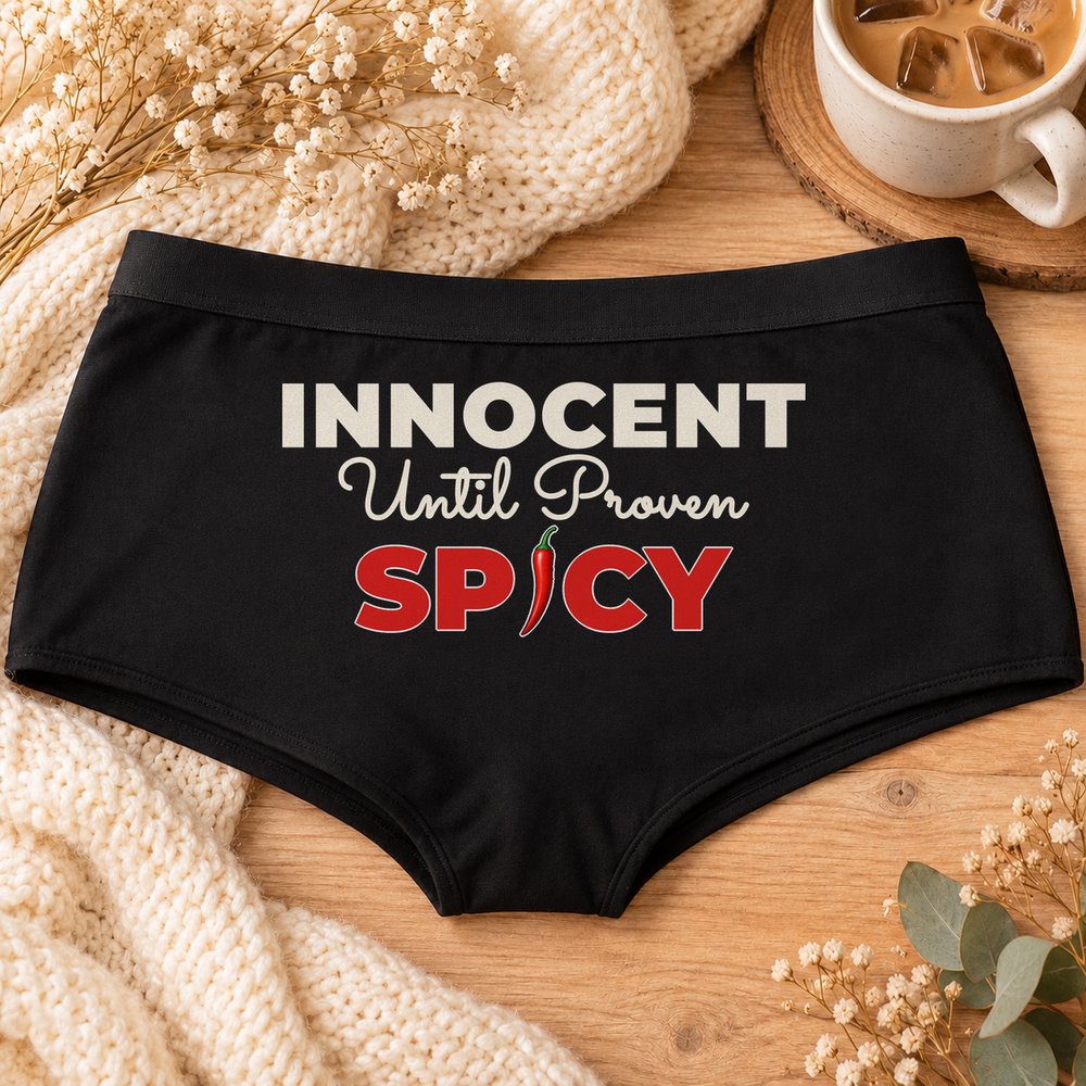 Innocent Until Proven Spicy panties – black boyshort underwear with "Innocent Until Proven Spicy" saying, flat-lay