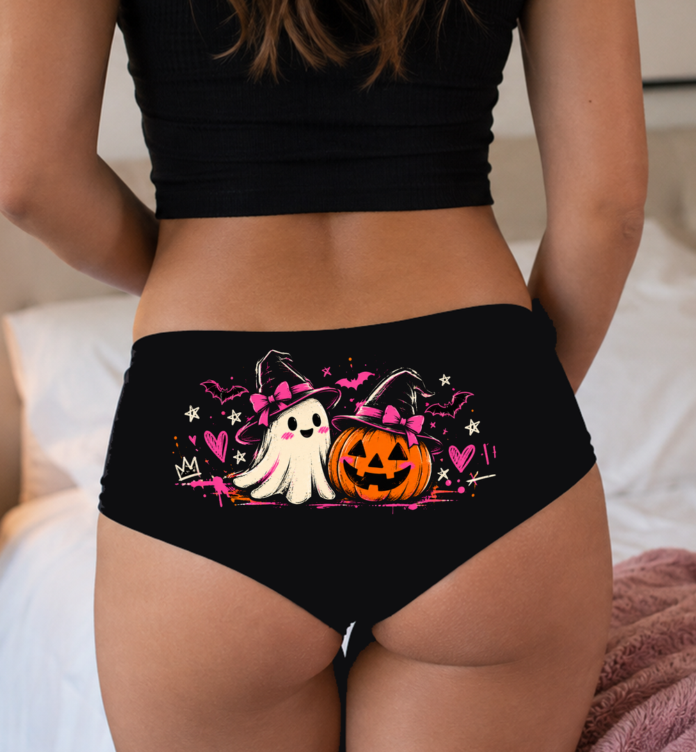 Model in a top wearing black boyshorts with the witch-hat ghost and pumpkin print