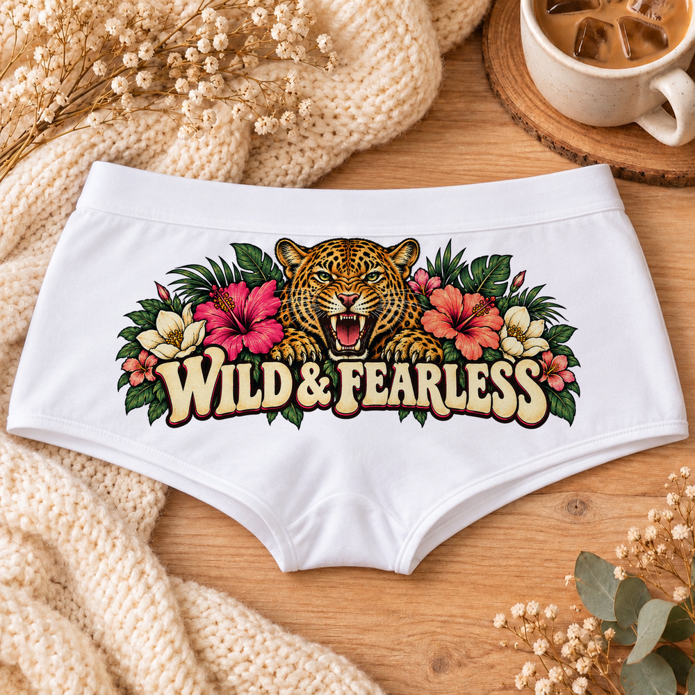 White Wild & Fearless leopard print boyshort underwear with a roaring leopard, hibiscus flowers, tropical leaves and cream Wild & Fearless lettering, flat-lay