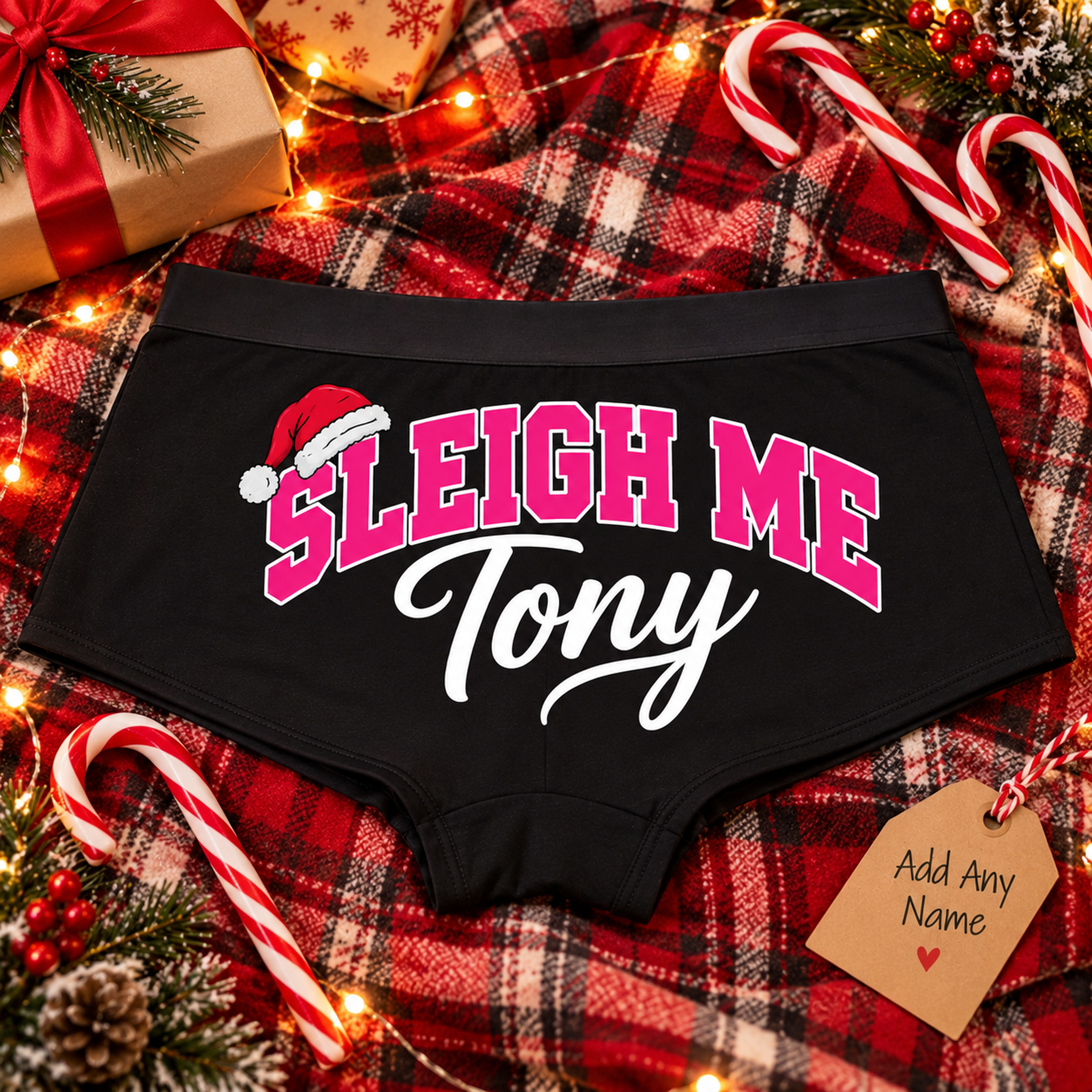 Black Sleigh Me custom name boyshort panties with pink lettering and Santa hat on a Christmas plaid blanket