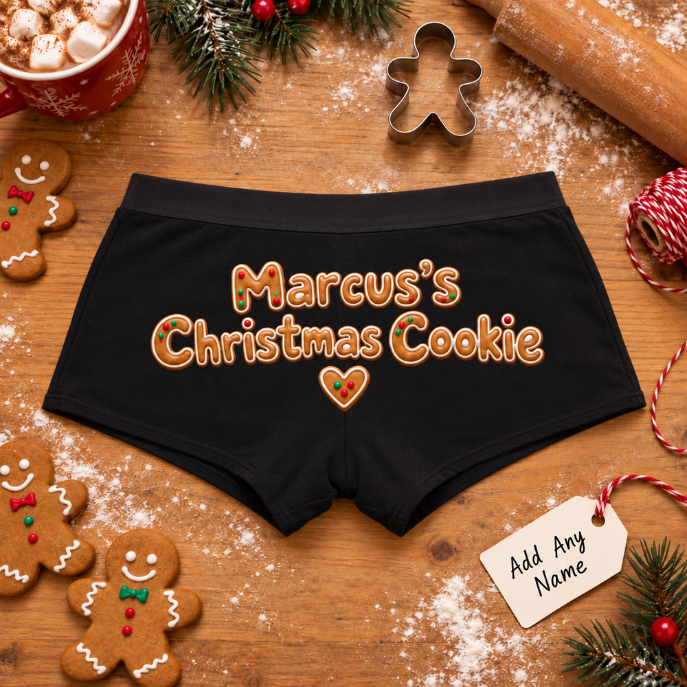 Personalized black boyshort panties printed “Marcus's Christmas Cookie” in iced gingerbread lettering, on a wood table with gingerbread cookies (any name can be added)