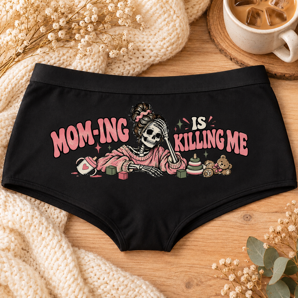 Black Mom-ing Is Killing Me funny mom boyshort underwear with a messy-bun skeleton mom in a pink sweater, toys and pink lettering, flat-lay