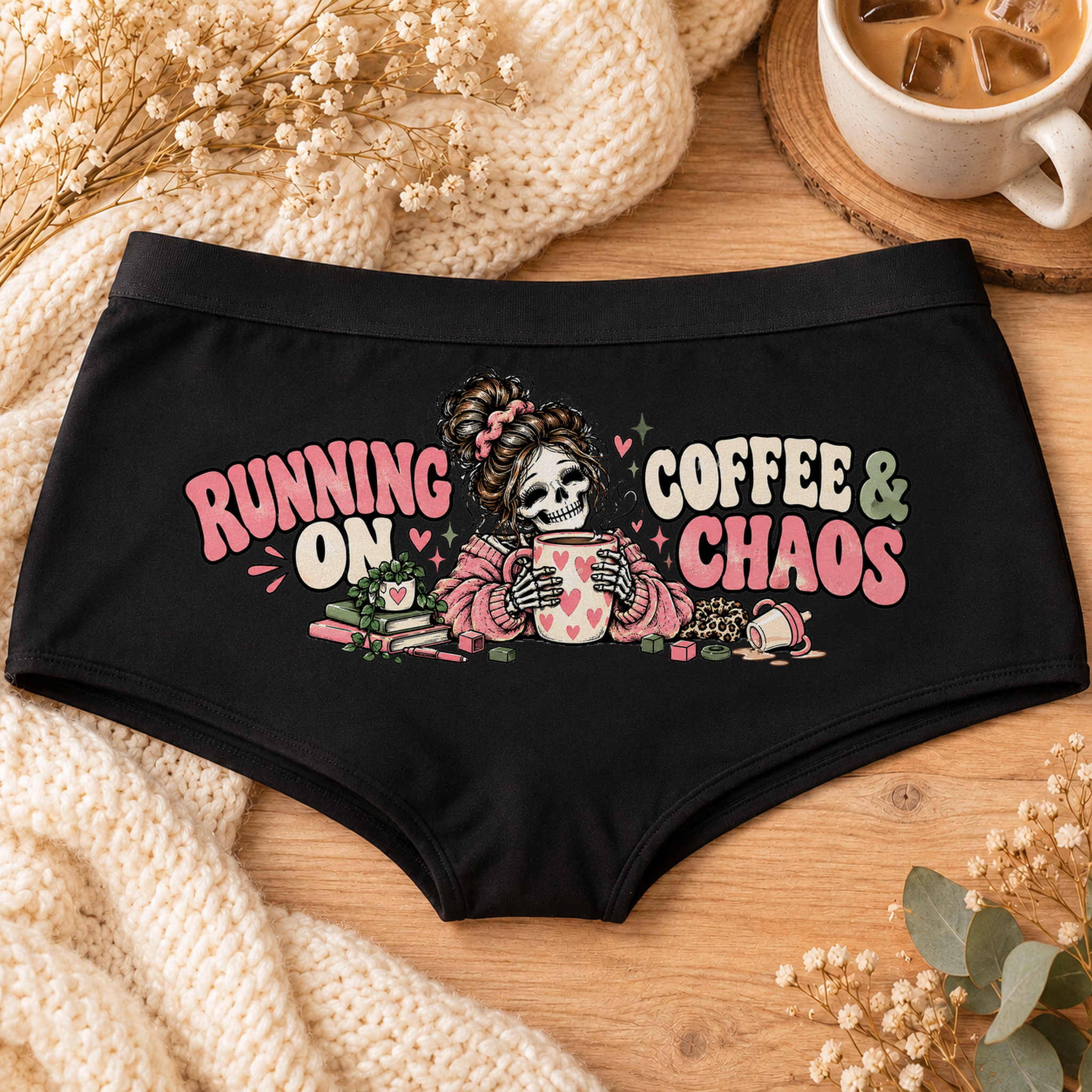 Black Running on Coffee & Chaos tired mom boyshort underwear with a messy-bun skeleton mom holding a heart coffee mug, pink and sage lettering, flat-lay