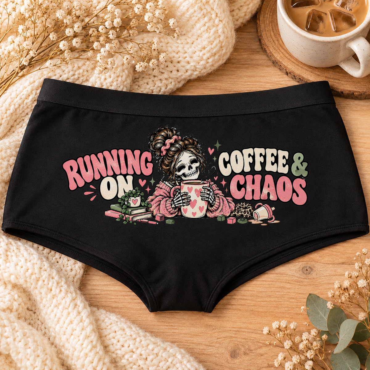 Black Running on Coffee & Chaos tired mom boyshort underwear with a messy-bun skeleton mom holding a heart coffee mug, pink and sage lettering, flat-lay